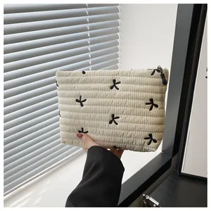 Detail der gesteppten cremefarbenen Kosmetiktasche mit schwarzen Schleifen-Stickereien