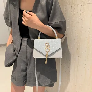 Sac à main bleu clair scintillant avec logo SS doré porté par un mannequin en blazer