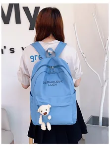 Vue arrière d'un sac à dos en nylon bleu clair avec un adorable pendentif ours en peluche