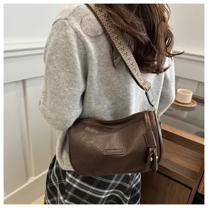 Close-up of brown PU leather pillow bag with stylish ethnic woven shoulder strap