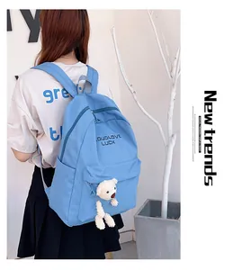 Détail du sac à dos bleu en nylon avec texte Goodlove Luck et breloque ours en peluche