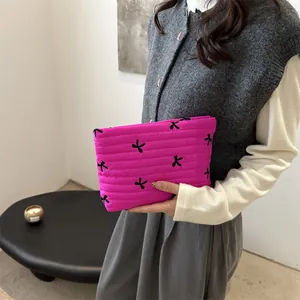 Gesteppte rosa Kosmetiktasche mit schwarzen Schleifen in der Hand eines Models
