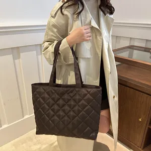 Grand sac cabas matelassé en nylon marron porté par un mannequin en trench-coat