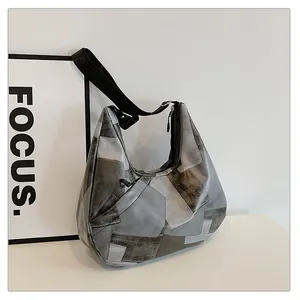 Dettaglio della borsa hobo patchwork grigia con ampia tracolla regolabile su sfondo bianco