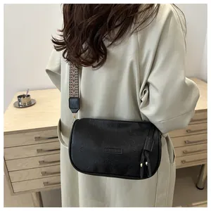 Fashionable black pillow bag with textured leather, fringe tassels and woven strap