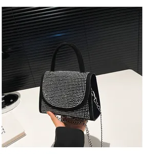 Detail of elegant black mini handbag featuring a sparkling rhinestone flap and silver chain