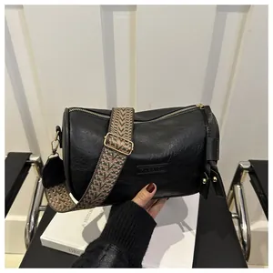 Detail of black Boston bag with lychee texture leather and geometric woven strap