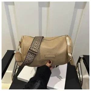 Detail of khaki cylinder bag featuring a textured leather finish and jacquard strap