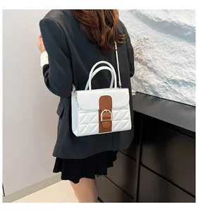 Close-up of a white and brown quilted crossbody bag shown on a model in a formal suit