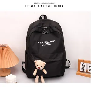 Détail du sac à dos en nylon noir avec texte blanc et accessoire d'ours en peluche