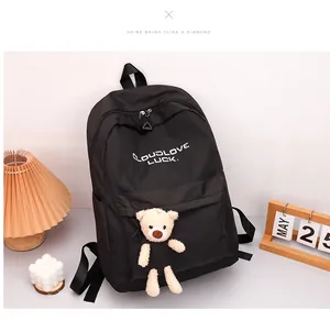 Détail du sac à dos noir imperméable avec lettrage blanc et pendentif ours en peluche