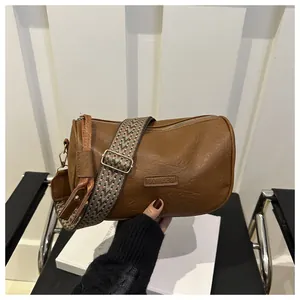 Macro shot of brown cylinder pillow bag featuring a retro ethnic style woven strap