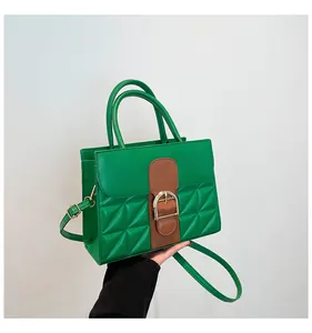 Detail of green quilted crossbody bag with vintage brown strap and gold buckle