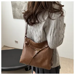 Close-up of vintage brown leather tote bag with gold buckle on a model shoulder