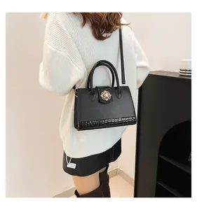 Detail of black crossbody bag featuring gold flower clasp and crocodile texture base