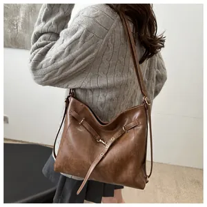 Brown vintage faux leather tote bag worn by model in a cozy winter knit sweater