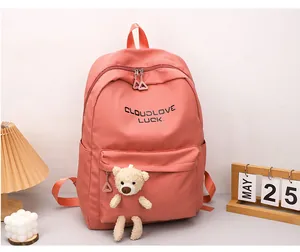 Détail du sac à dos rose corail avec breloque ours en peluche et lettrage sur le bureau