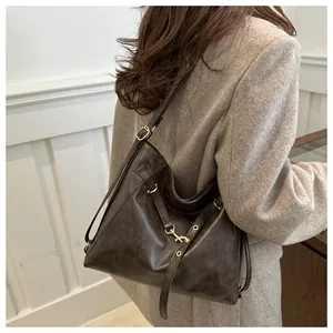Detail of vintage brown leather tote bag with gold metal buckle and adjustable strap