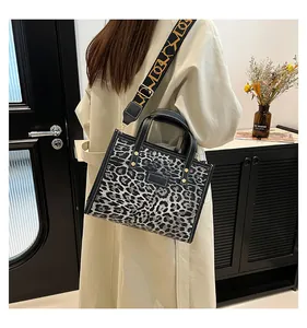 Detalle del bolso tote de leopardo con correa ancha geométrica y costuras blancas