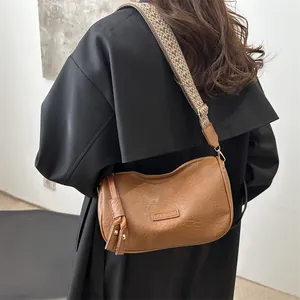 Fashionable caramel brown pillow bag with woven strap and gold hardware on black coat