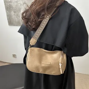 Minimalist beige half-moon pillow bag with a wide ethnic pattern woven shoulder strap