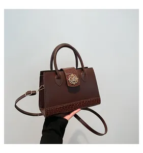 Detail of dark brown handbag showing crocodile texture contrast and golden flower buckle