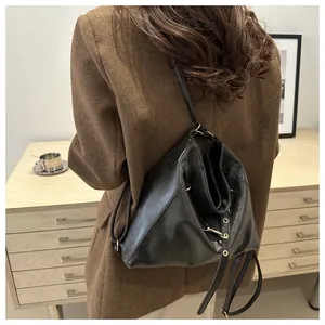 Detail of black leather bucket bag with gold buckle worn with a brown blazer