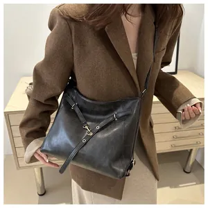 Close-up of black leather tote bag with elegant golden metal buckles and textured finish