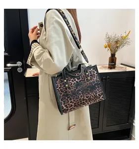Detalle del bolso tote de leopardo con ribete de cuero negro y correa ancha con estampado