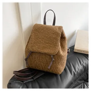 Detailed view of brown plush fleece backpack with leather straps on a sofa