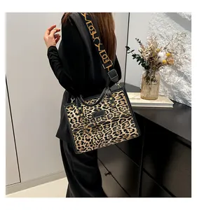 Detalle del bolso tote de leopardo con ribete de cuero negro y correa ornamentada