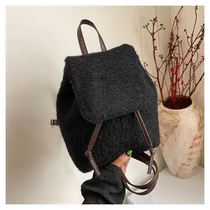 Detail of black faux shearling backpack with brown leather handle and drawstring closure