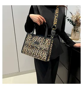 Detalle de bolso tote de leopardo con borde negro y correa de hombro ancha estampada