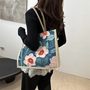 Artistic tote bag with pink floral relief and blue canvas, styled for daily commuting