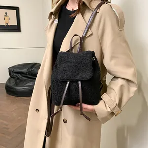 Chic black plush mini backpack with brown faux leather straps shown on a model