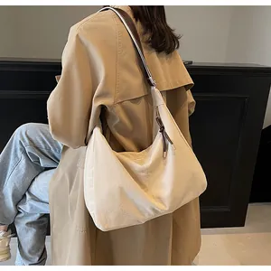 Detailed view of beige suede hobo bag with dark adjustable strap and tassel zipper detail