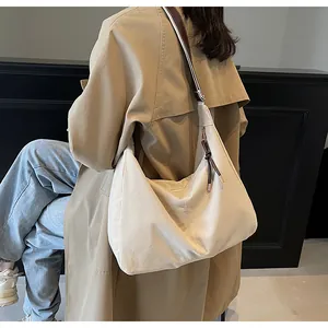 Model wearing a minimalist cream canvas tote bag with a striped adjustable shoulder strap
