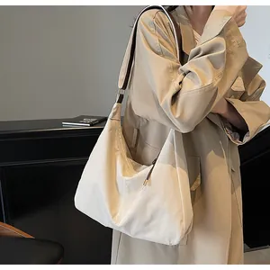Model wearing a large cream canvas tote bag with a khaki trench coat for a casual look