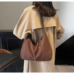 Detail view of large brown canvas hobo tote bag worn with an adjustable strap