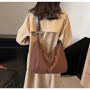 Detail view of large dark brown canvas tote bag with white stitching on beige coat