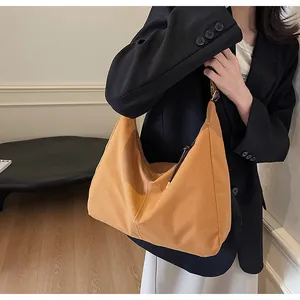 Detail of a large mustard yellow suede hobo shoulder bag styled with a dark blazer