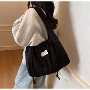 Détail du cabas en velours côtelé noir avec cordon de serrage et étiquette minimaliste