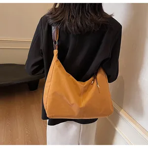 Detail of a large orange canvas hobo bag with contrast stitching and leather strap