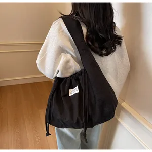 Détail du sac à bandoulière en velours côtelé noir avec cordon et grande capacité de rangement