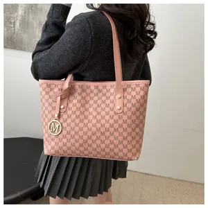 Detailed close-up of pink monogram tote bag with gold M-shaped pendant and rivets
