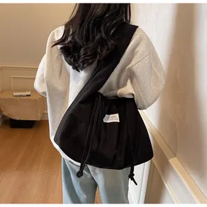 Gros plan d'un sac bandoulière en velours côtelé noir avec cordon de serrage et sangle