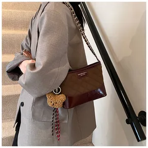 Détail du sac bandoulière en tissu matelassé, garniture cuir et charm d'ours