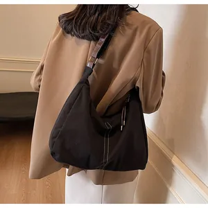 Detail of a large black canvas tote bag with white stitching shown on a person