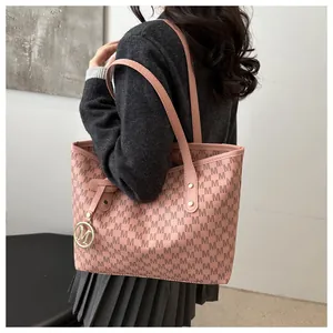Detail of pink tote bag with M-pattern monogram, gold charm and slim shoulder straps