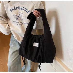 Détail du sac cabas en velours côtelé noir avec cordon de serrage et étiquette minimaliste